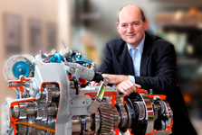 Technikübersetzer Martin Ritschel stützt sich auf das Getriebe eines allradgetriebenen Kleinlastkraftwagens.